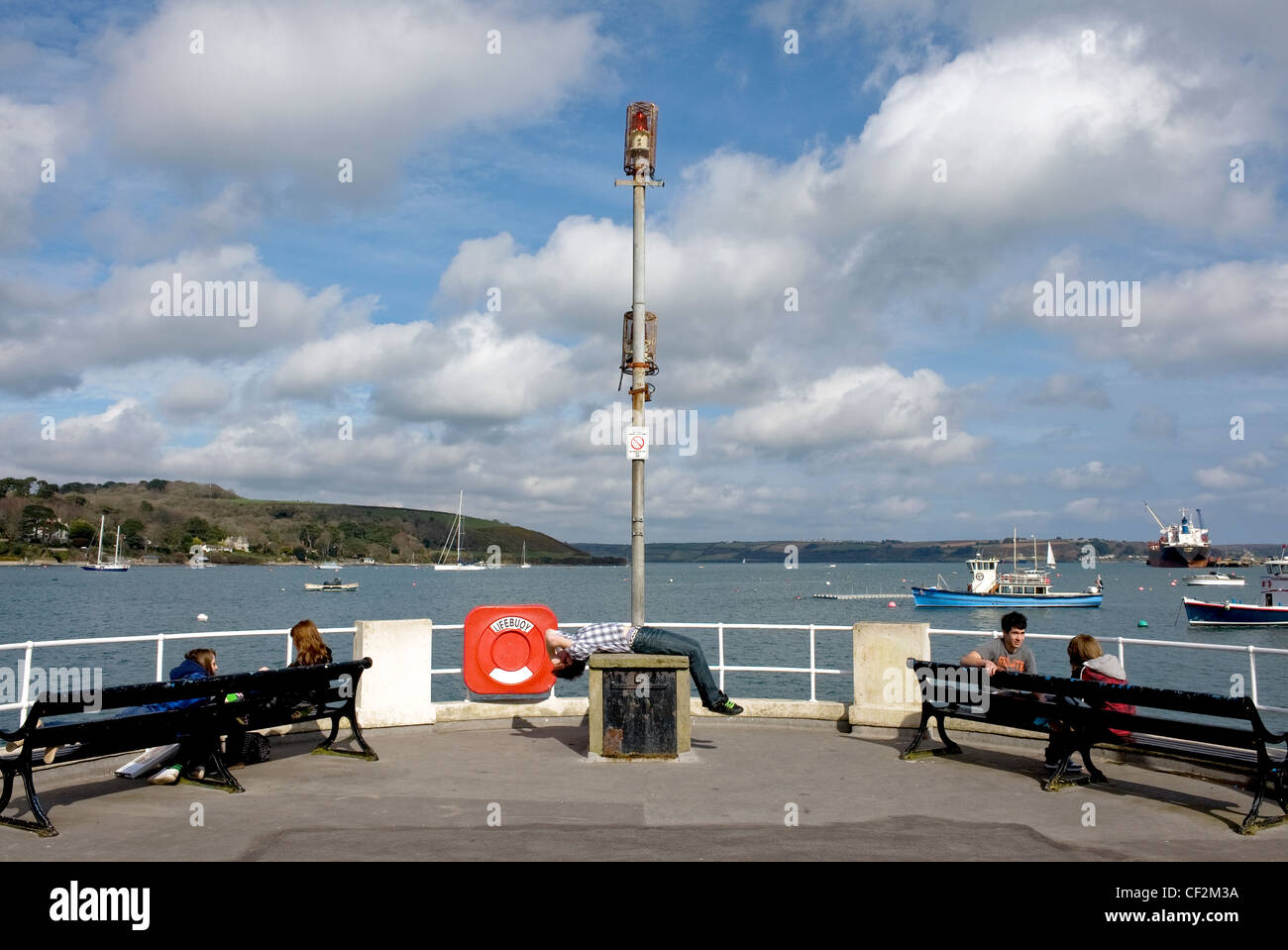 Teenagers sitting at the end of the Prince of Wales Pier in Falmouth. Falmouth and nearby Carrick Roads form the third deepest n Stock Photo