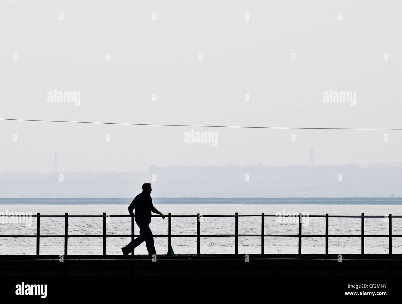 The silhouette of a man walking along a gantry. Stock Photo