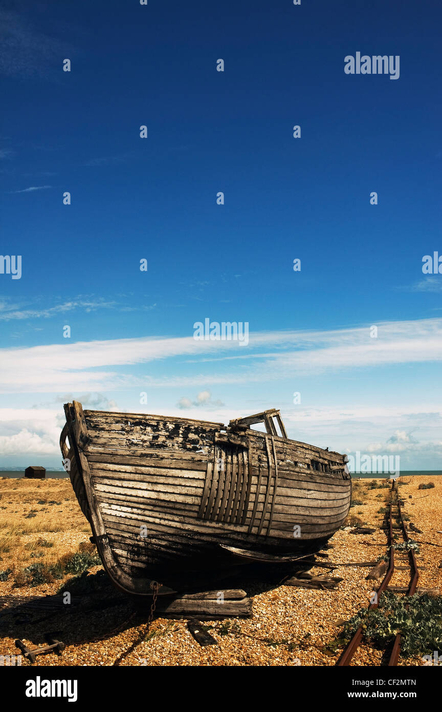 An abandoned wooden fishing boat beached on the shingle beach at ...
