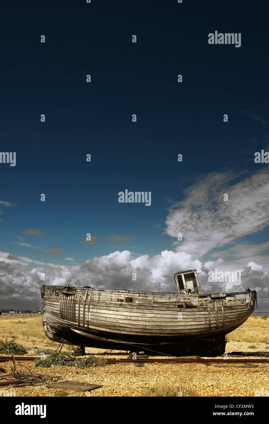 An abandoned wooden fishing boat beached on the shingle at Dungeness ...
