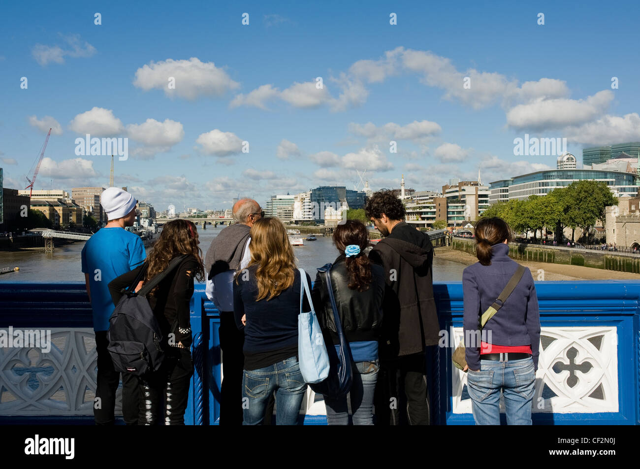 A group of tourists standing on Tower Bridge looking west along the River Thames. Stock Photo