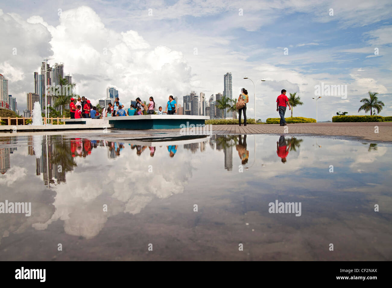 skyline and passersby reflected in a puddle on the refurbished seafront promenade of Cinta Costera and the of Panama City, Stock Photo