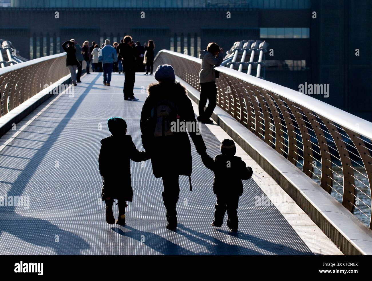 A mother and children crossing the Millennium Bridge over the River Thames. Stock Photo
