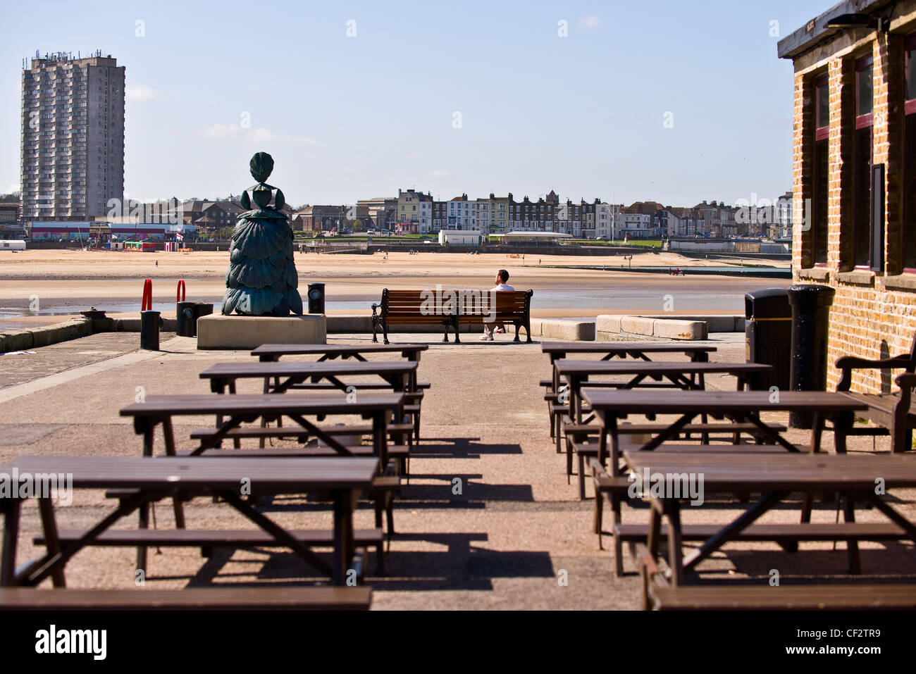 Trestle tables outside the Lighthouse bar. A nine feet high bronze sculpture of Mrs Booth, the Shell Lady of Margate by Ann Carr Stock Photo