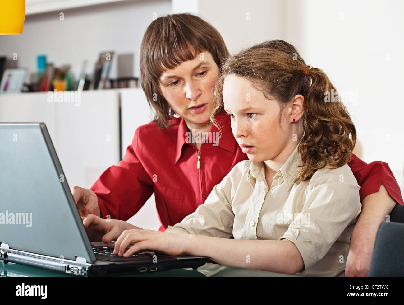 Mother and teenager girl with laptop computer together at home Stock Photo