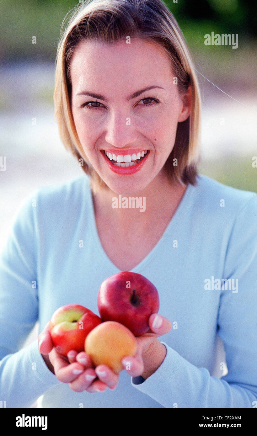 Female Shoulder Length Blonde Hair Wearing Blue Top Holding An Apricot