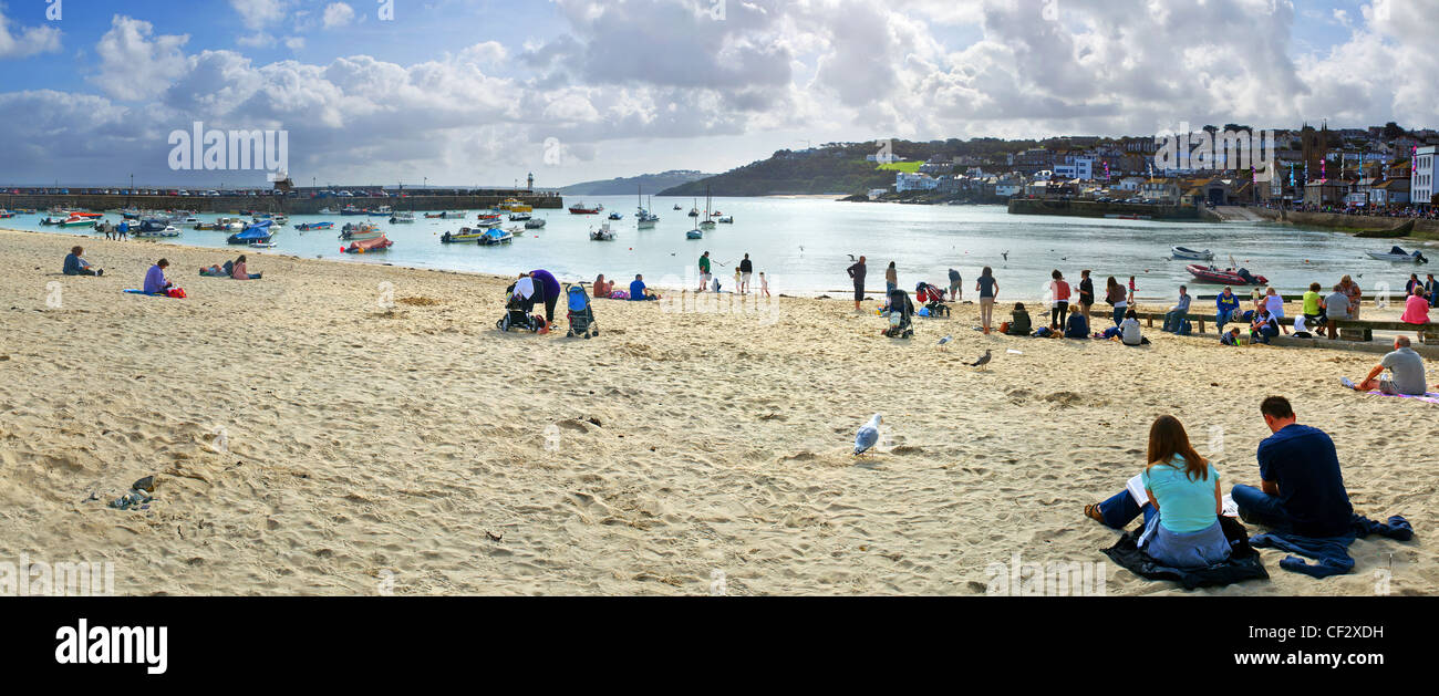People relaxing on the sandy beach by St Ives Harbour. Stock Photo
