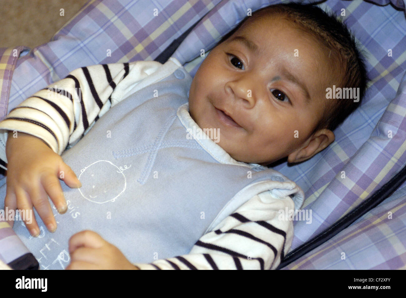 Male child wearing white and black striped babygrow blue bib lying