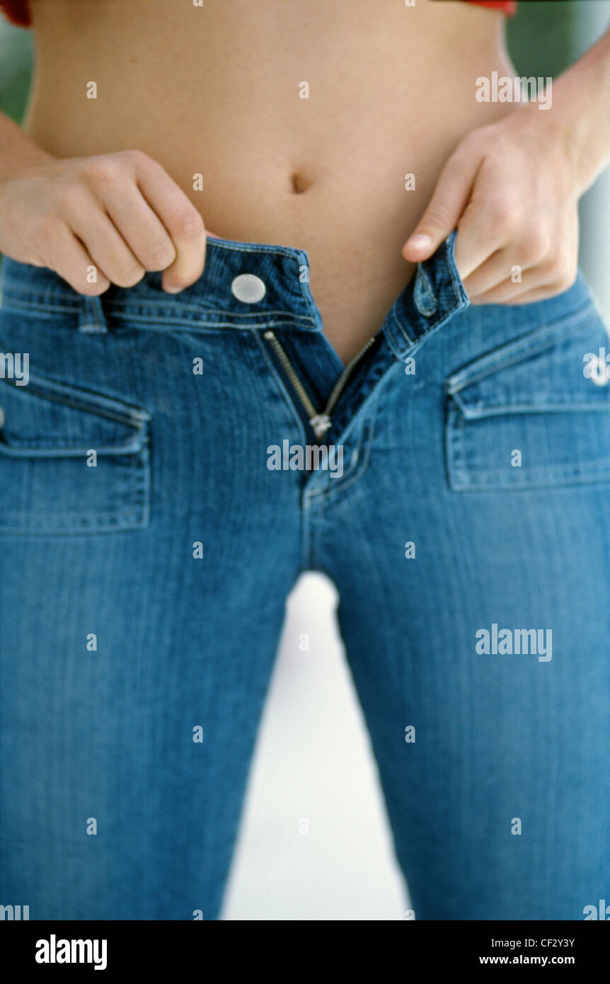 Female wearing tight blue jeans trying to do up trousers Stock Photo - Alamy