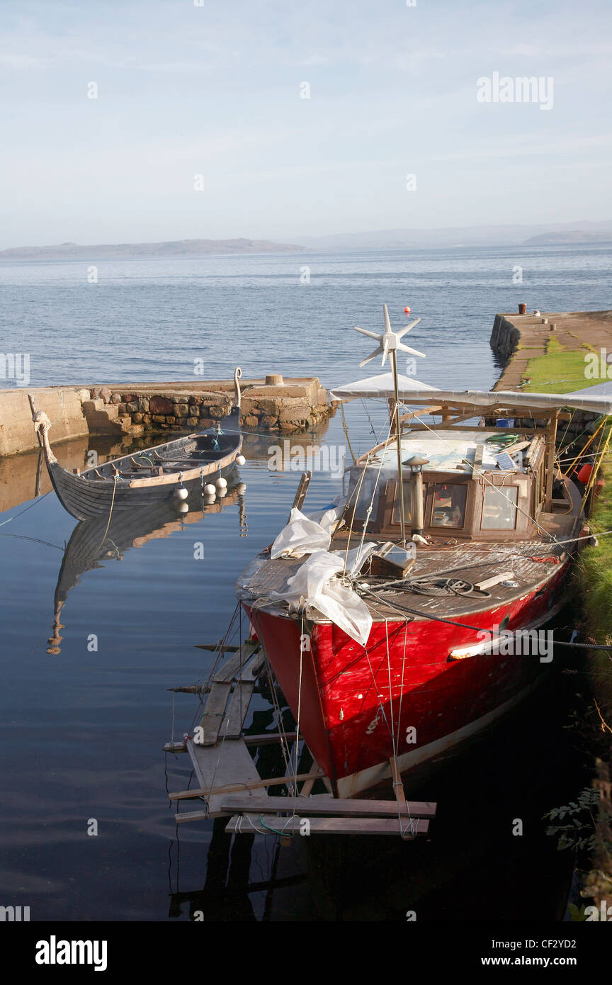 A fishing boat and replica Viking boat in Corrie Harbour on the Isle of Arran. Stock Photo