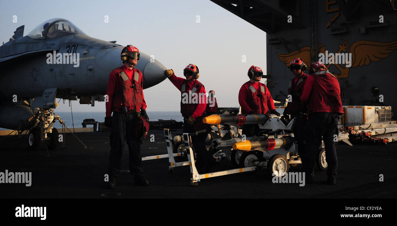ARABIAN SEA (Feb. 27, 2012) Aviation ordnancemen wait to load a skid of AIM-9 Sidewinder air-to-air missiles onto an F/A-18C Hornet assigned to the Vigilantes of Strike Fighter Squadron (VFA) 151 on the flight deck of the Nimitz-class aircraft carrier USS Abraham Lincoln (CVN 72). Abraham Lincoln is deployed to the U.S. 5th Fleet area of responsibility conducting maritime security operations, theater security cooperation efforts and support missions as part of Operation Enduring Freedom. Stock Photo