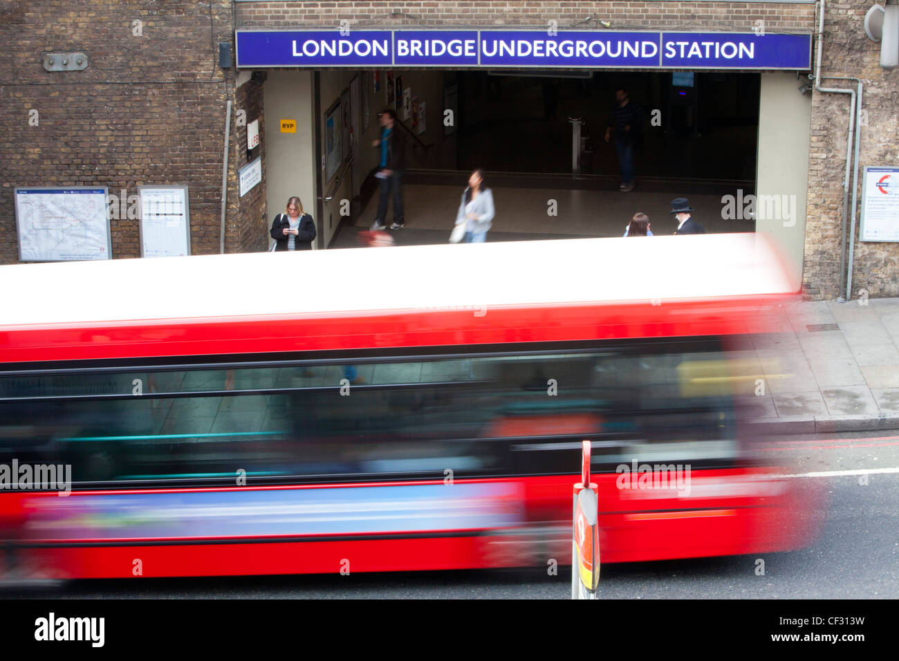 A view of a tradional red London bus as it passes London Bridge underground station Stock Photo