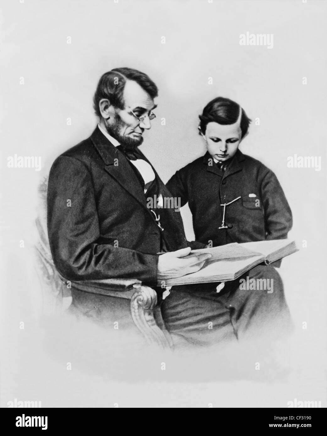 President Abraham Lincoln, seated, and son Thomas (Tad) standing, looking at album made by Mathew B. Brady on February 9, 1864 Stock Photo