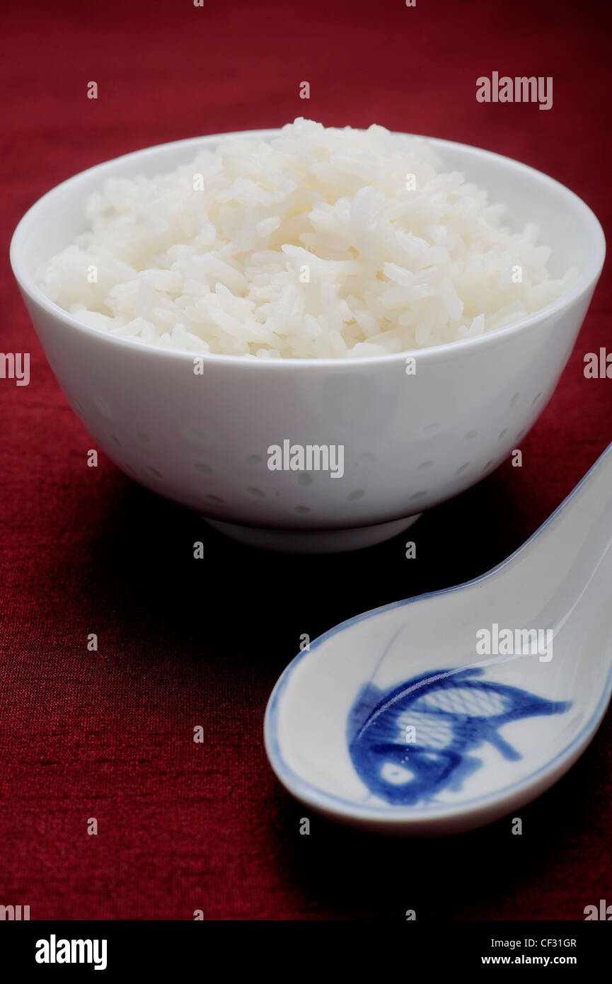 A bowl of boiled rice, with a white and blue china spoon Stock Photo