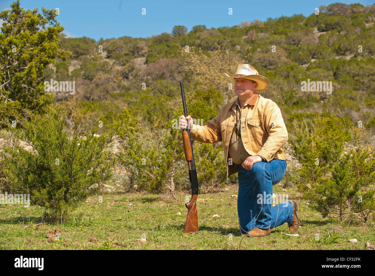 Texas cowboy with gun kneeling down Stock Photo