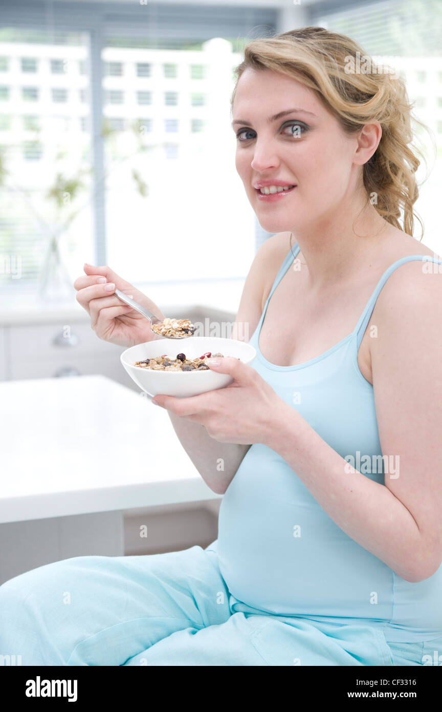Pregnant female fair hair tied at the back, wearing a blue vest
