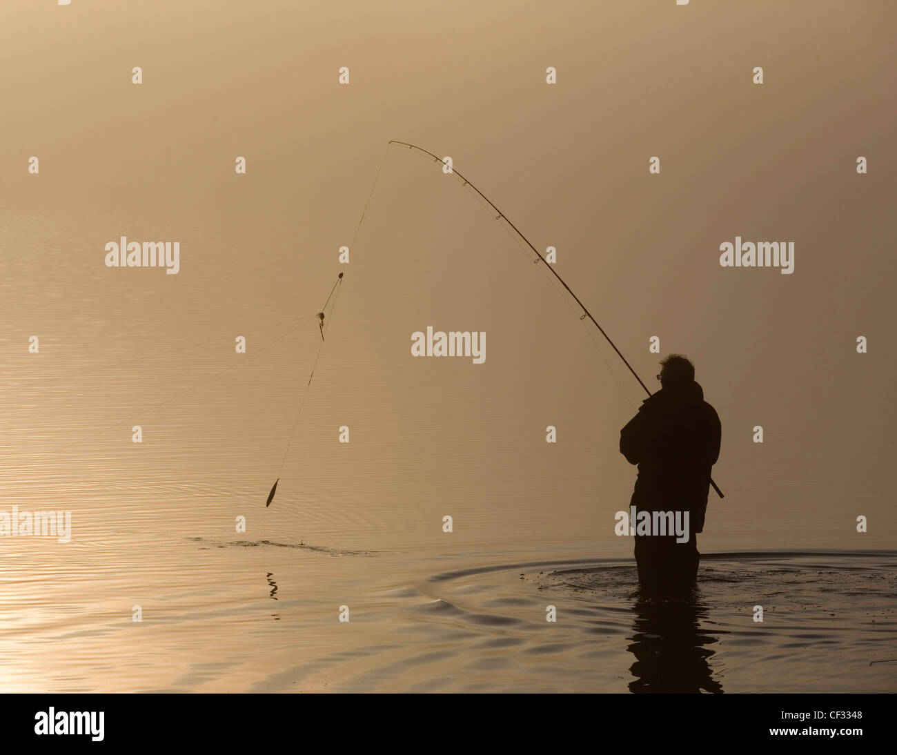 The silhouette of a lone angler fishing in Bassenthwaite Lake in the