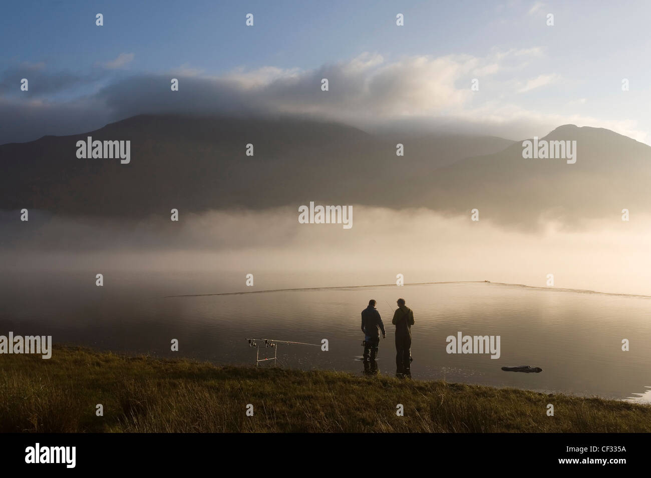 The silhouettes of two anglers fishing in Bassenthwaite Lake in the