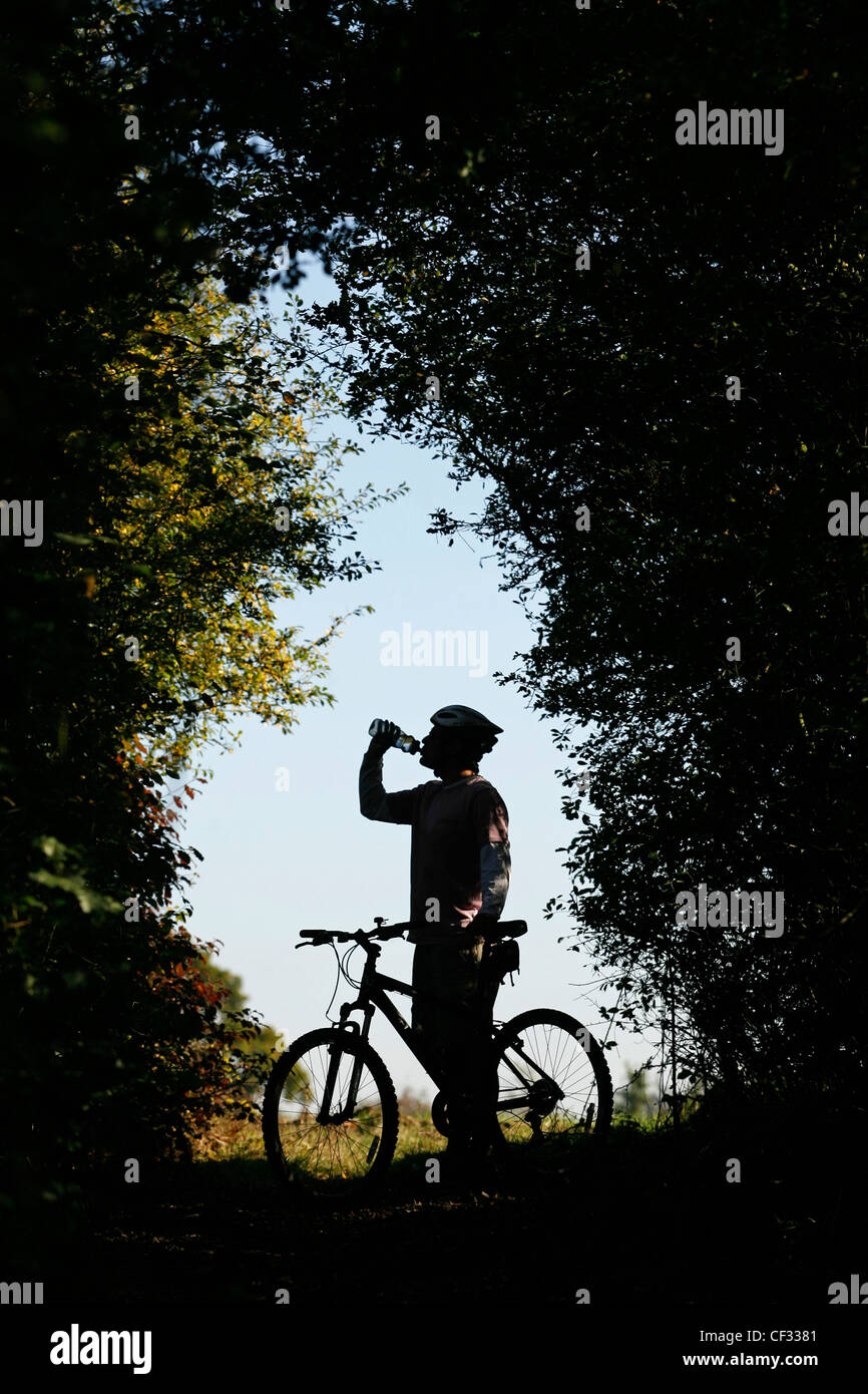 Silhouette of a mountain biker drinking from his water bottle. Stock Photo