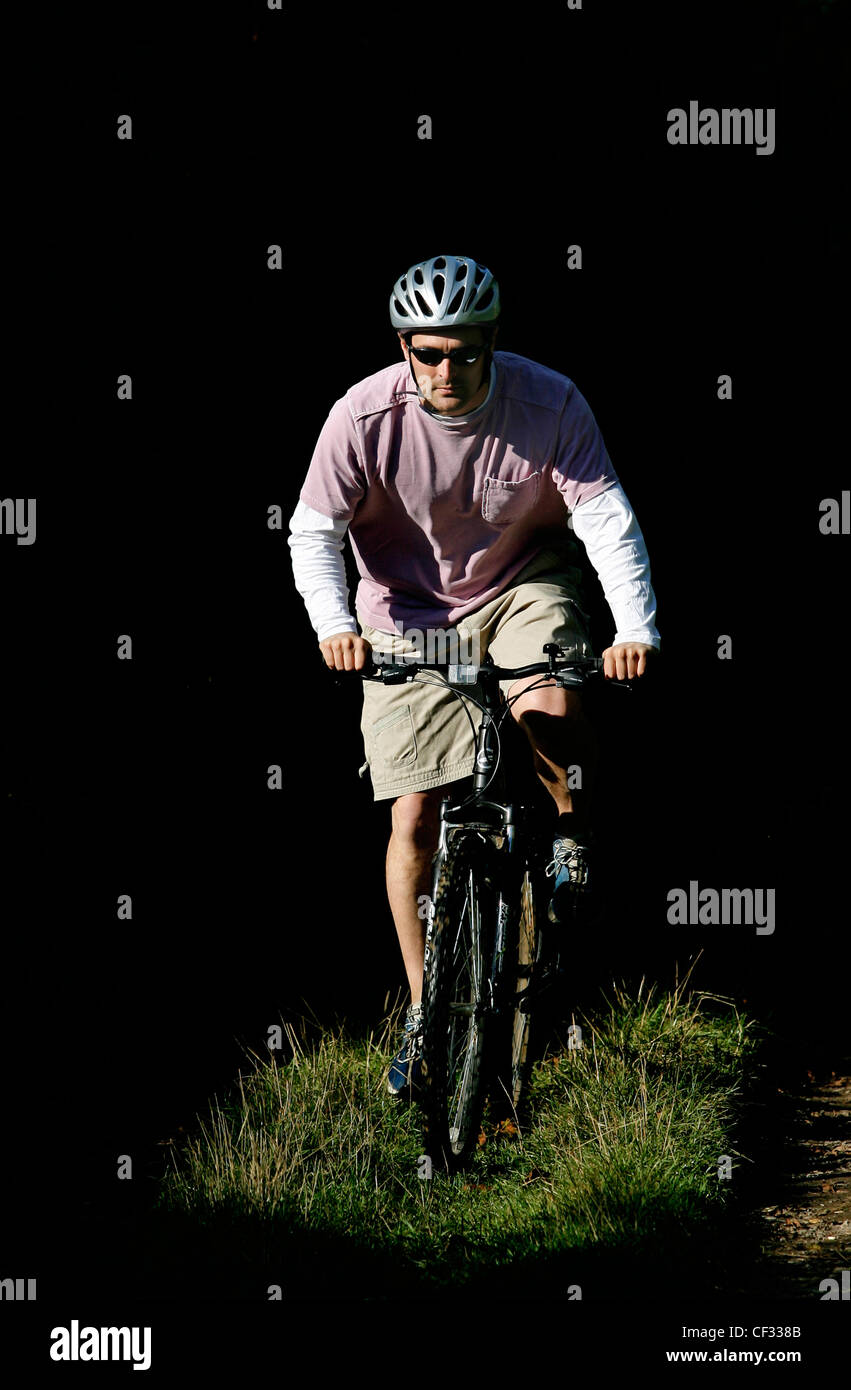 A man cycling through woodland on his mountain bike. Stock Photo