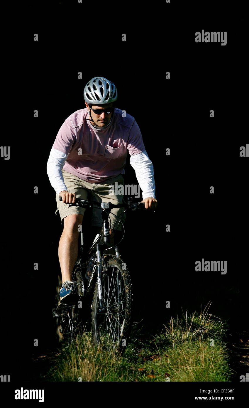 A man cycling through woodland on his mountain bike. Stock Photo