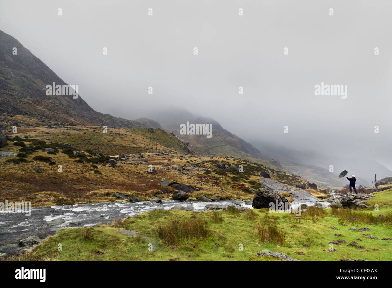 Battling the elements beside the afon or nant (river) peris at the top of the Llanberis pass in Snowdonia, Wales. Stock Photo