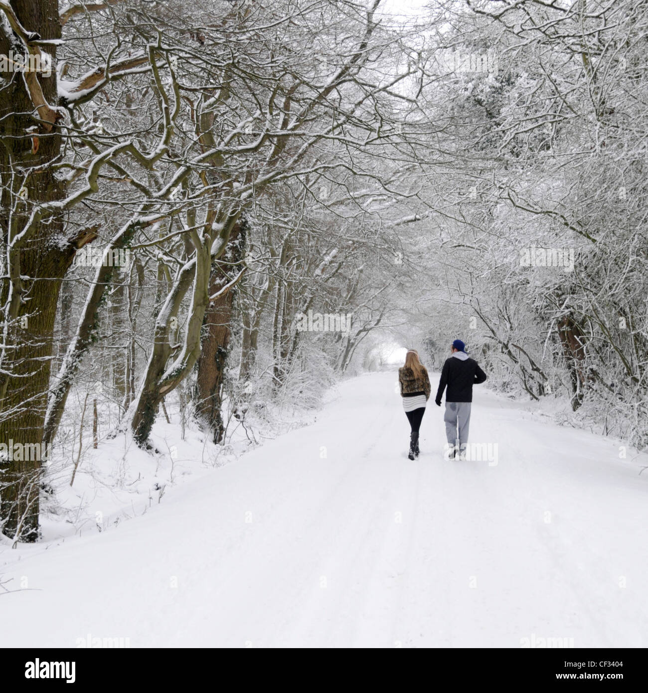 Young couple walking along country lane after heavy snowfall Stock Photo