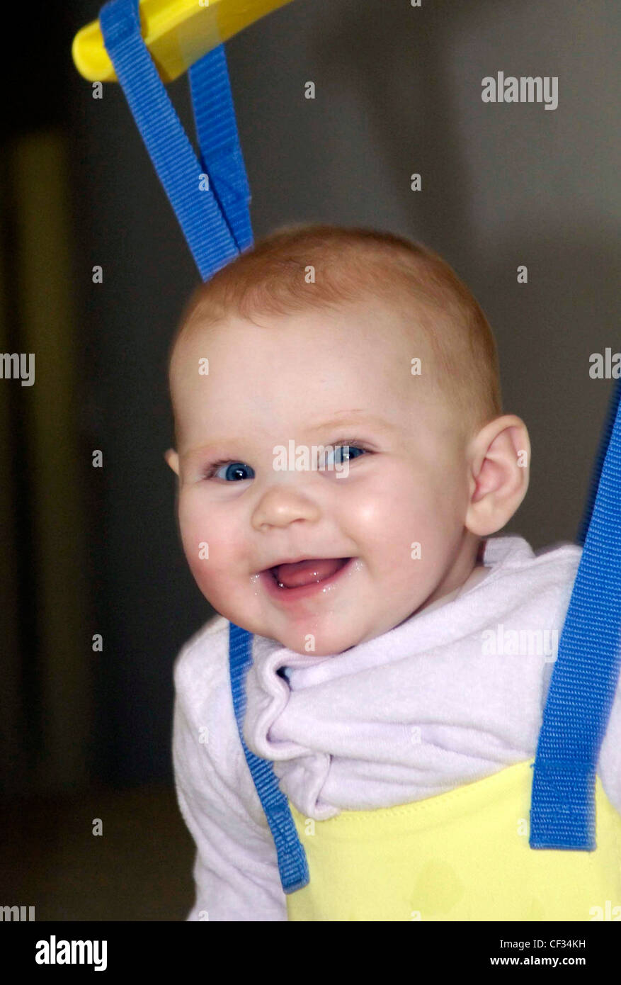 Female child sitting in bouncer looking to camera smiling Stock Photo Alamy