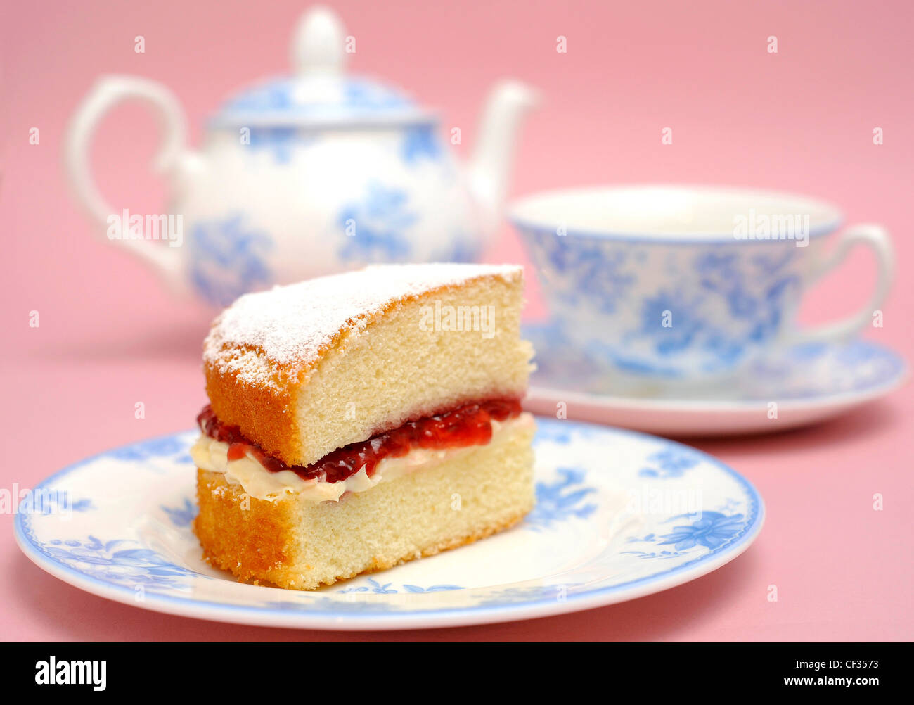 A white and blue patterned plate filled a slice of victoria sponge cake filled cream and strawberry jam, a blue and white Stock Photo