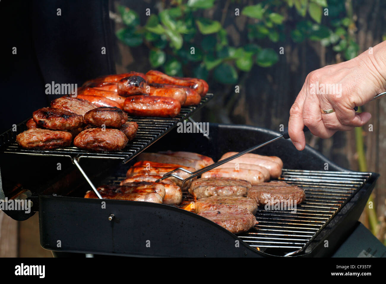 Sausages and burgers cooking on a barbecue. Stock Photo