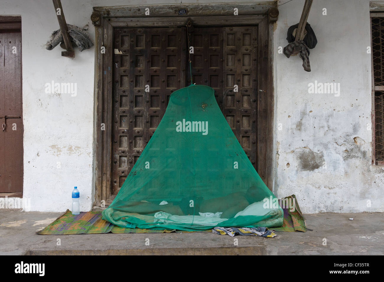 Man sleeping outside under a mosquito-net Stone Town Zanzibar Tanzania Stock Photo