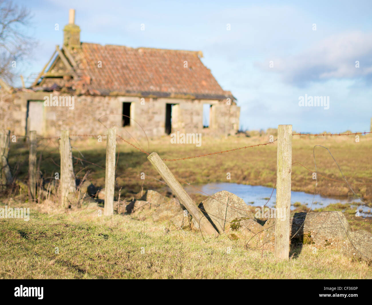 Derelict Cottage and Barbed Wire Fence Stock Photo