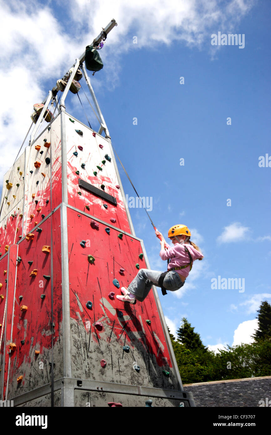A girl abseiling down a climbing wall. The origin of the abseil is