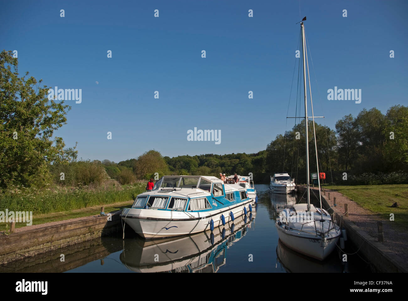 People relaxing on a boating holiday on the River Yare on the Norfolk Broads. Stock Photo