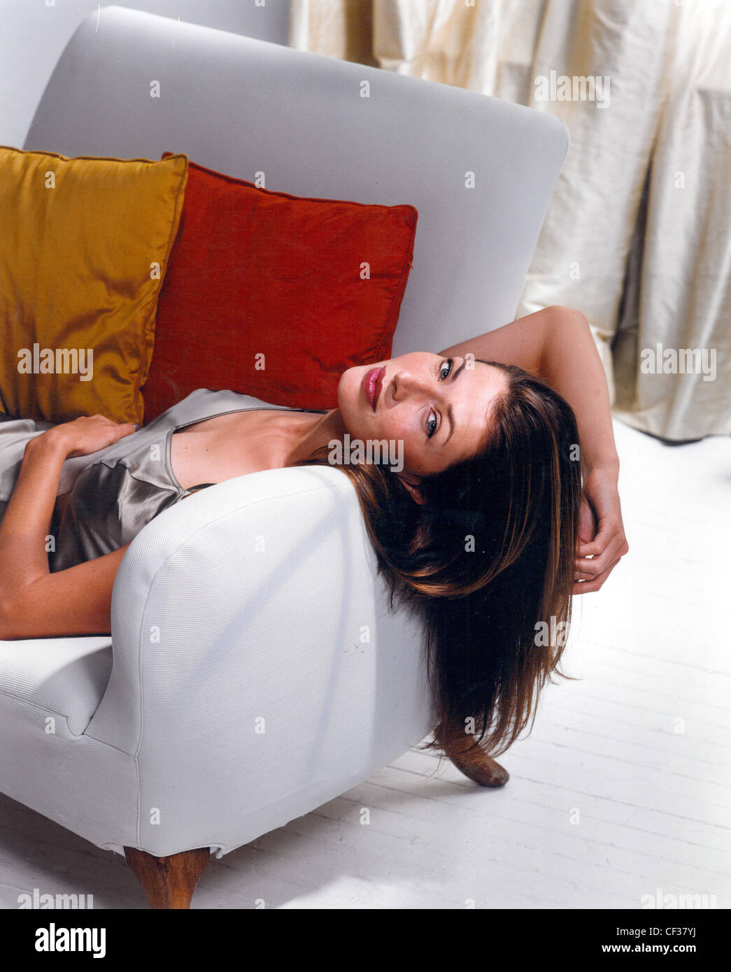 Female lying on armchair hair hanging over arm of chair Stock Photo