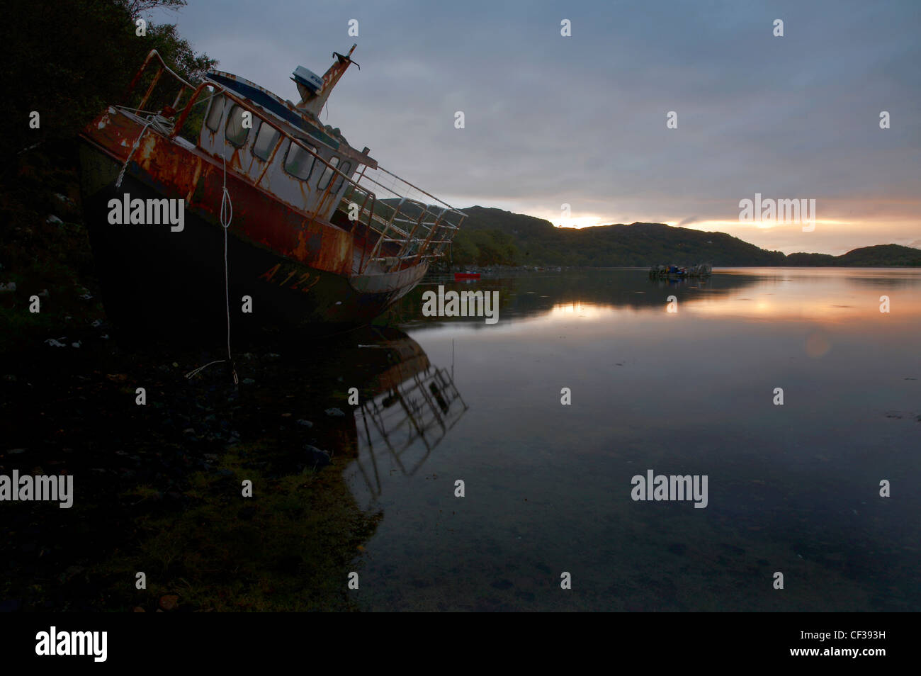 A beached boat at sunset on tranquil Loch Nedd. Stock Photo