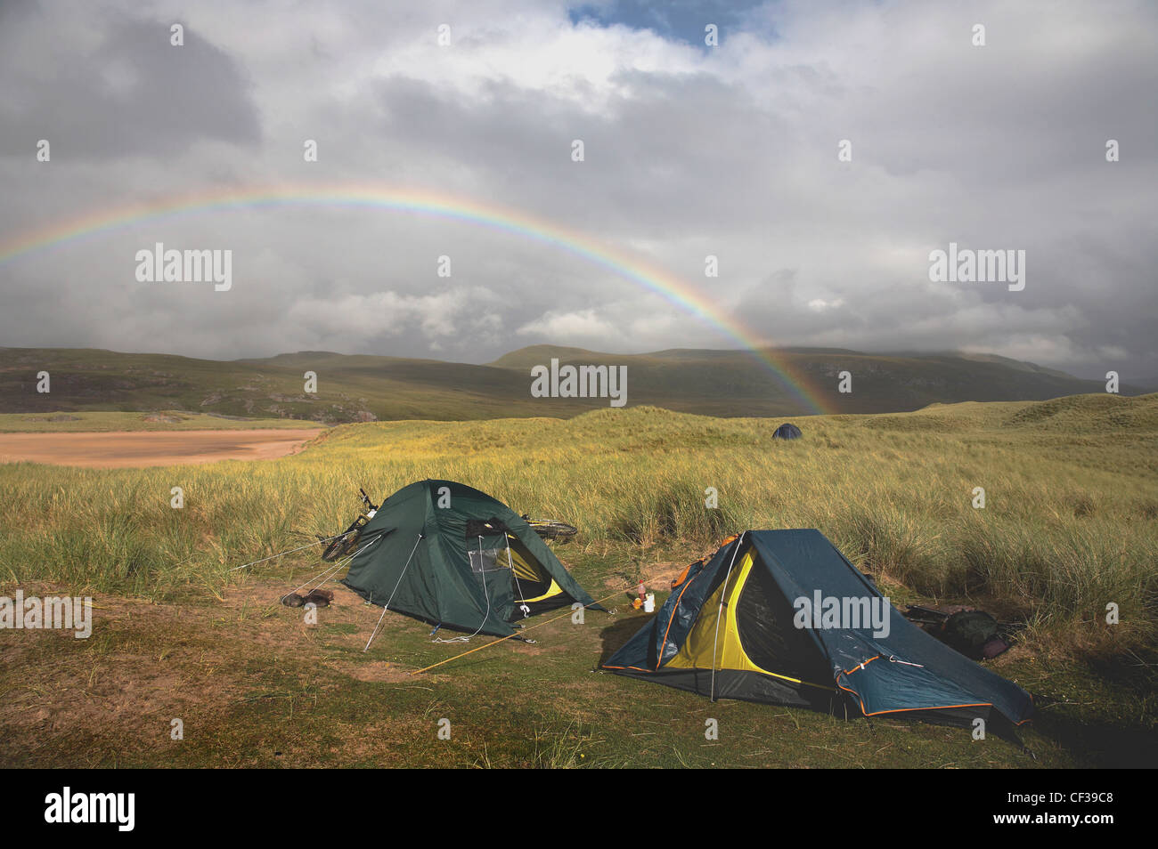 Tents on Sandwood Bay dunes with a rainbow in the distance. Stock Photo