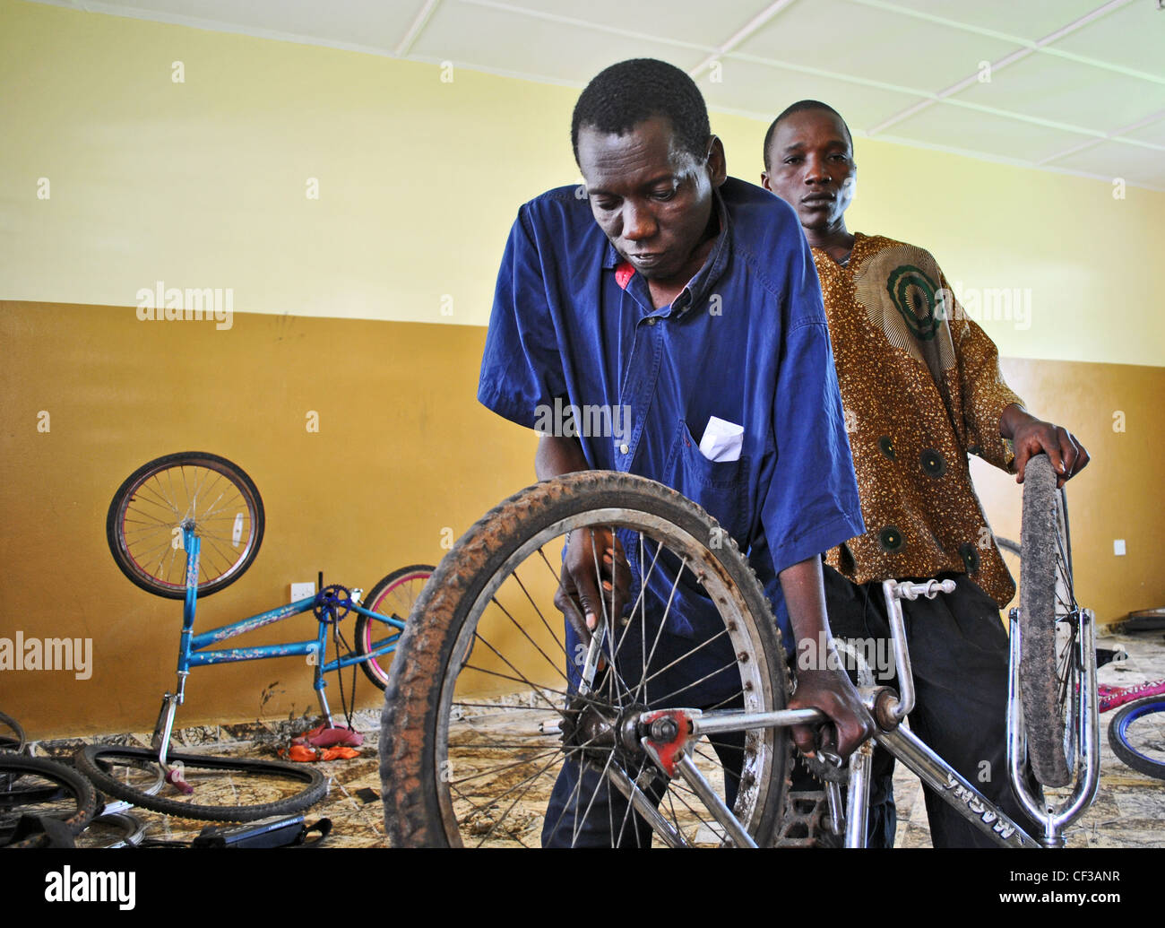A man with polio working as a bicycle mechanic in a UNDP-funded project in Makeni, Sierra Leone Stock Photo