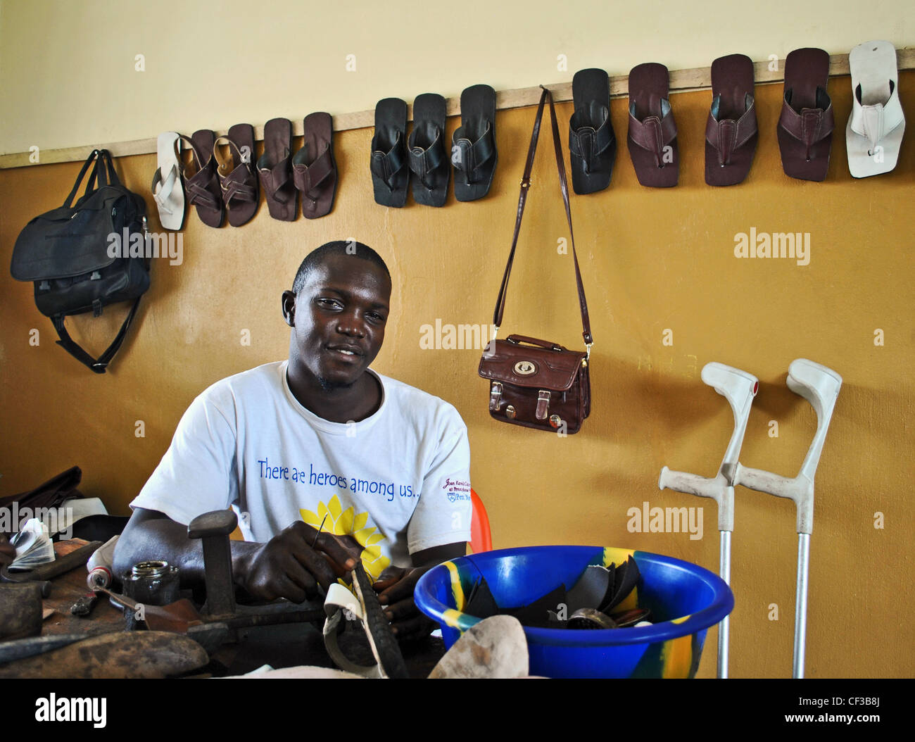 A man with polio makes sandals in a UNDP-funded employment project in Makeni, Sierra Leone Stock Photo