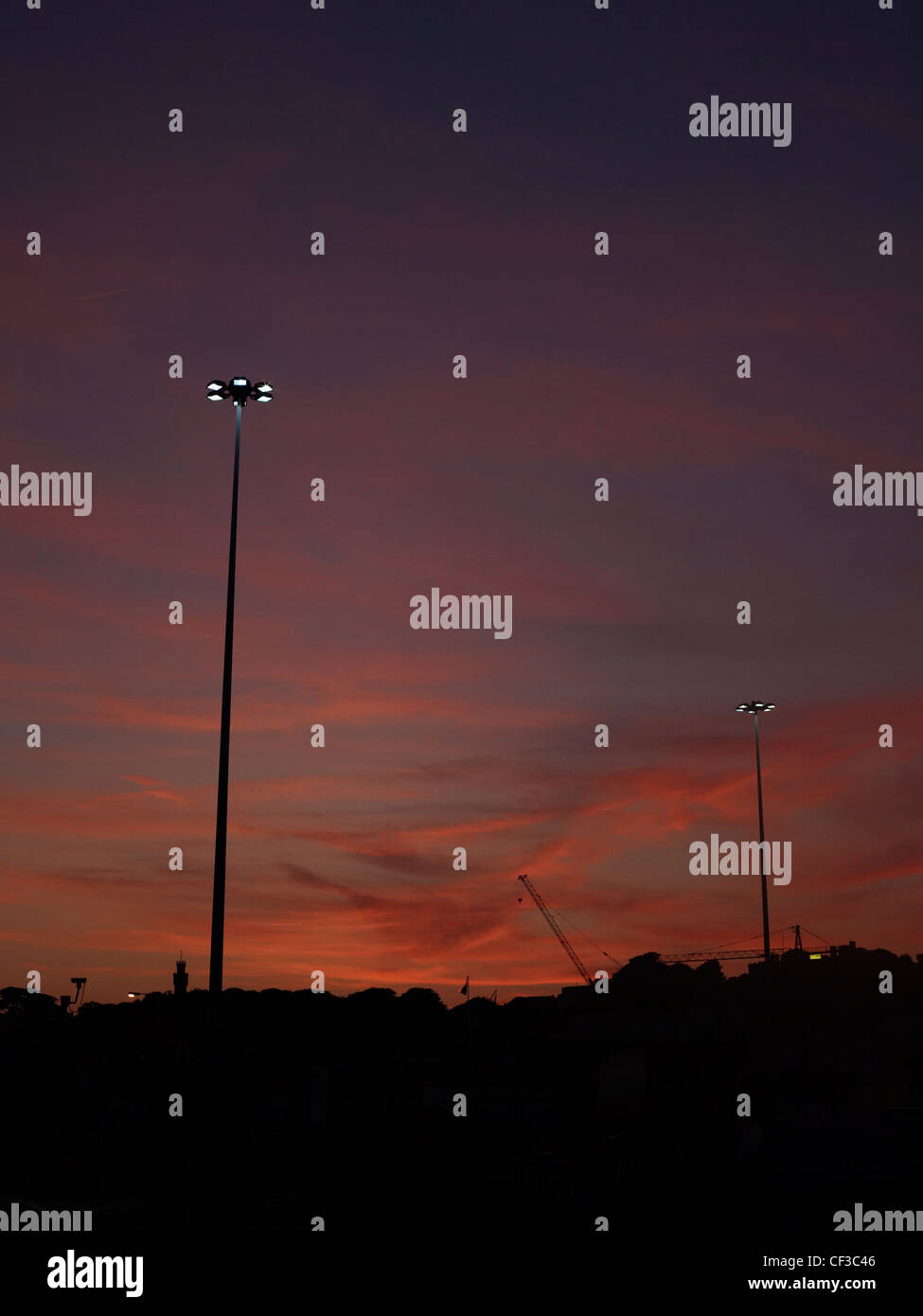 Two lighting towers silhouetted against an evening sky in Guernsey. Stock Photo