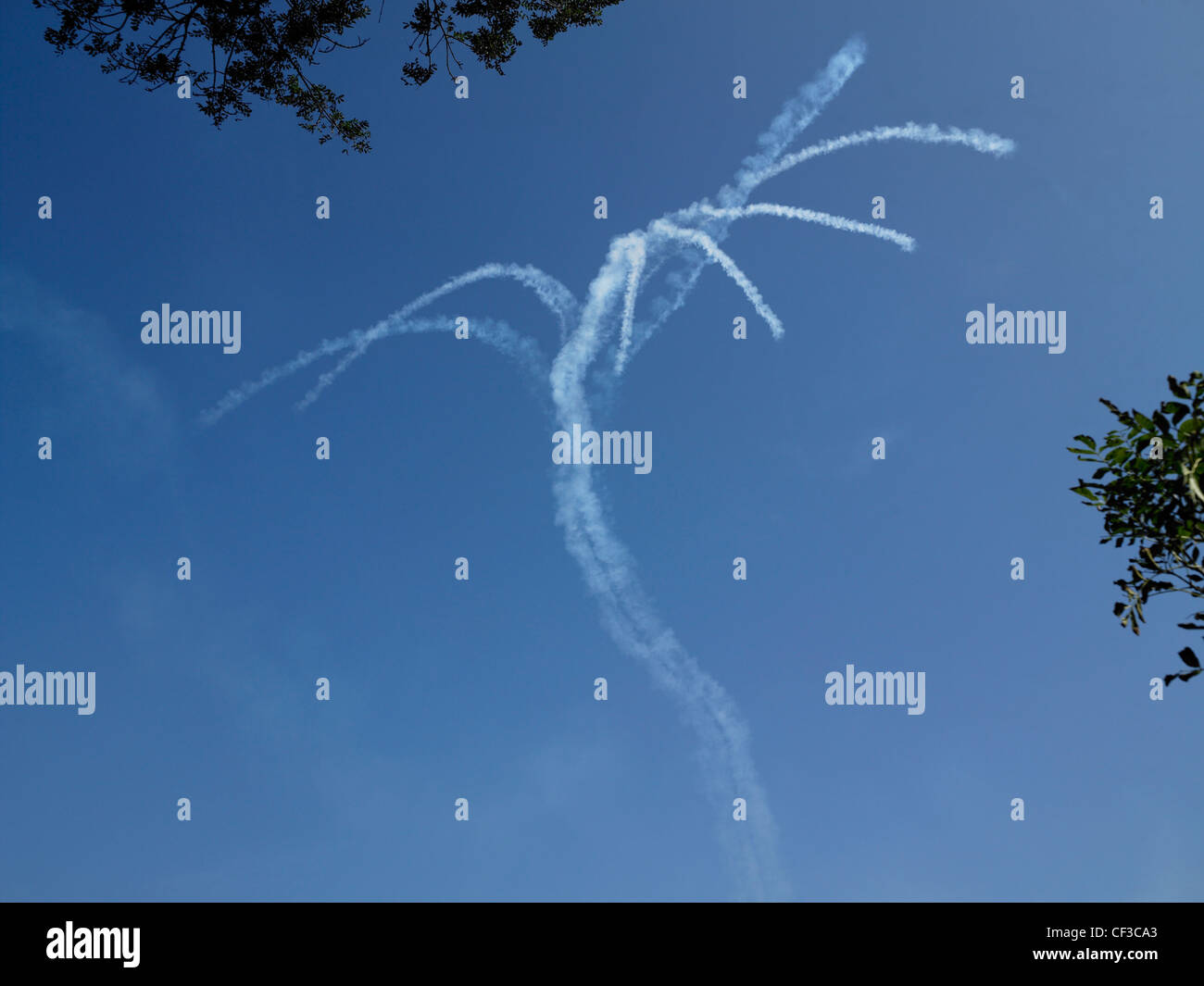 Smoke trails hang in the blue sky above Guernsey after a Red Arrows display. Stock Photo
