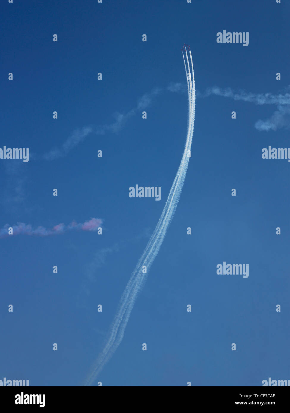 Smoke trails hang in the blue sky above Guernsey after a Red Arrows display. Stock Photo