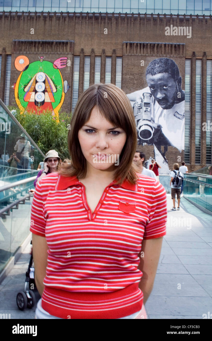 Female shoulder length brunette hair, wearing a striped red polo neck t shirt, standing on the south bank of the Thames in Stock Photo