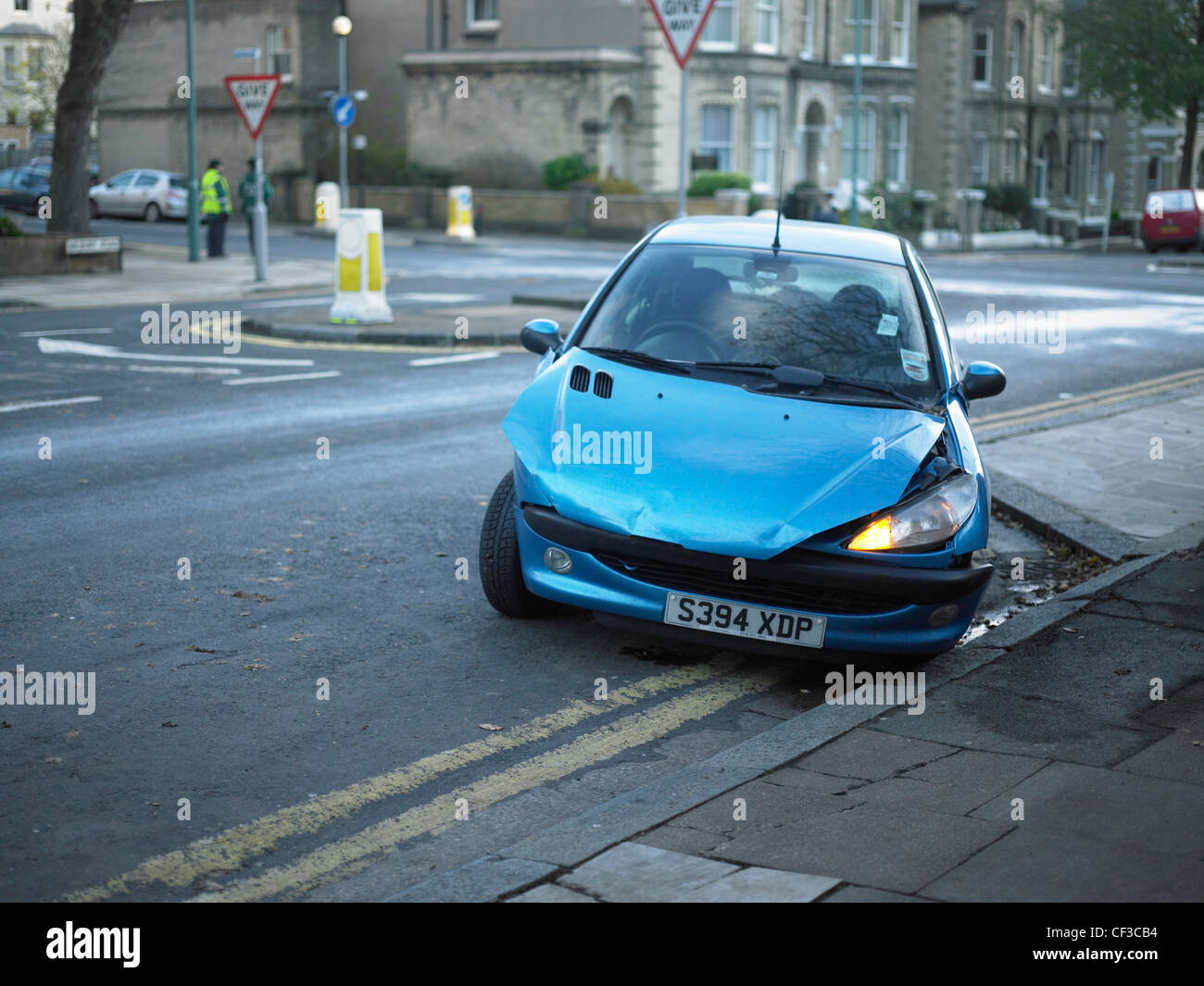 A damaged car sits abandoned next to a pavement in Hove. Stock Photo