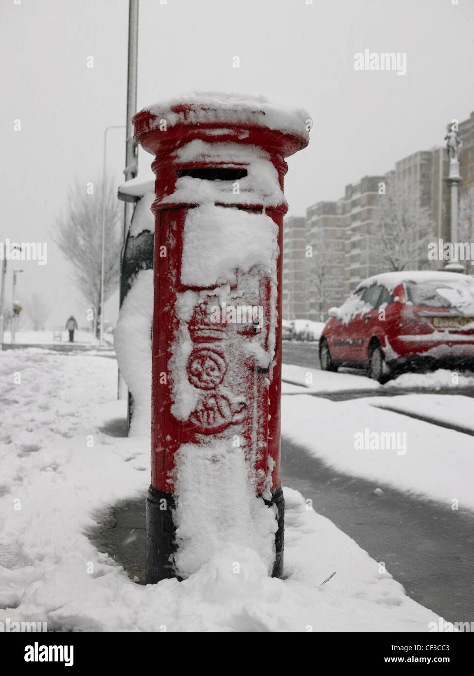 A red post box with a covering of snow in the streets of Hove. Stock Photo