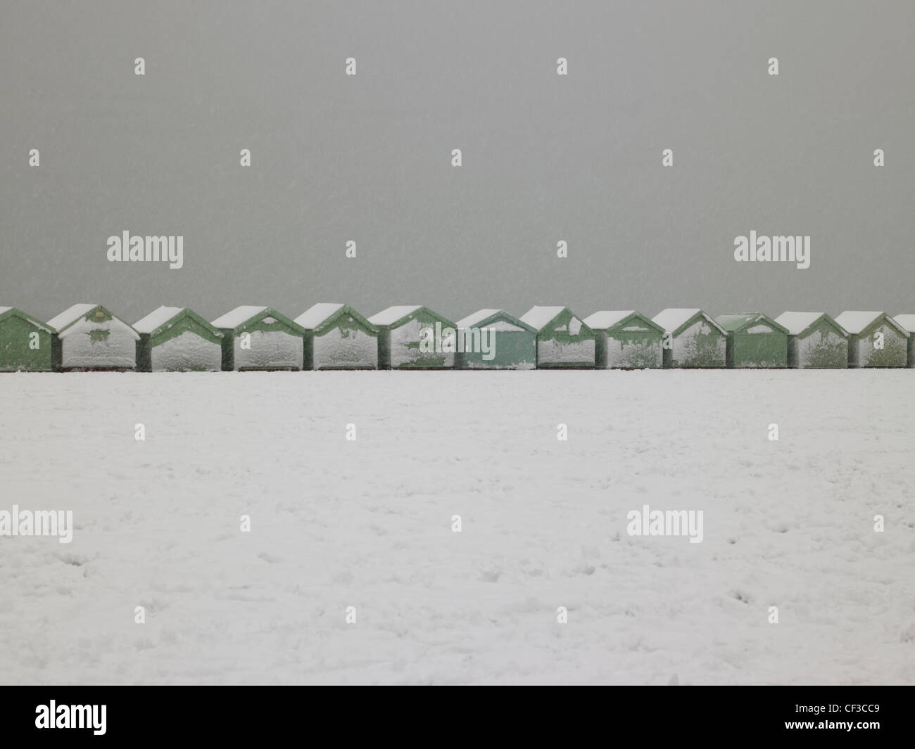 A view to a line of beach huts covered in snow in Hove. Stock Photo