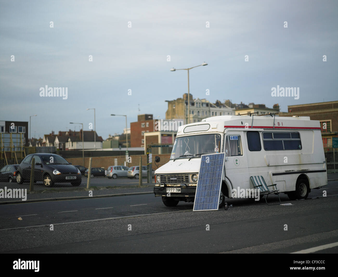 An old ambulance parked on the roadside with a solar panel and chair in Hove. Stock Photo