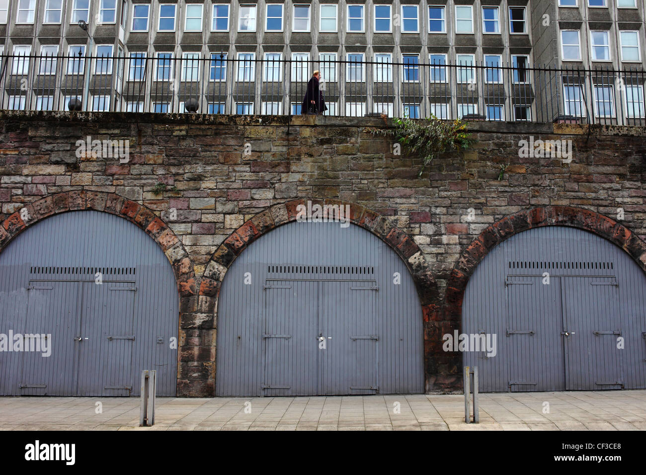 A woman walking along East Market Street above lock ups in the arches below Stock Photo Alamy