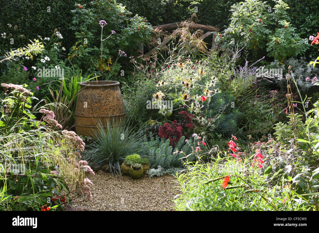 Summer garden gravel, pink poppies, large terracotta pot, potted plants