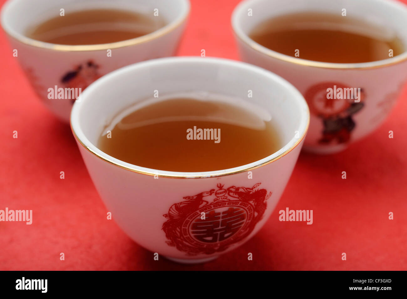 Three small chinese style patterned cups filled with green tea Stock Photo